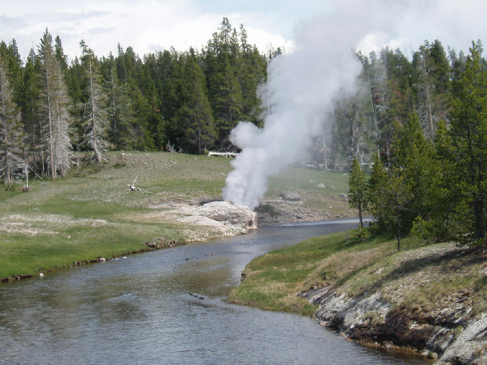 Riverside Geyser steaming beside Firehole River Yellowstone