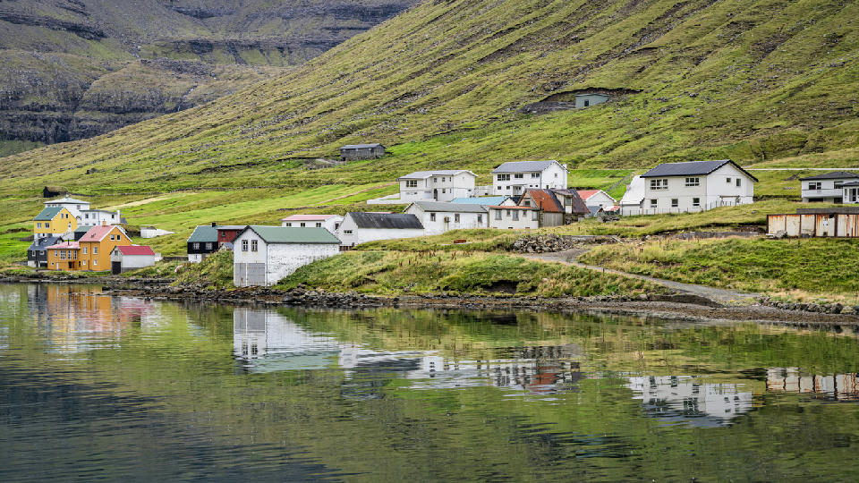 Norðdepil village on Borðoy Island in the Faroe Islands with houses reflected in the fjord.