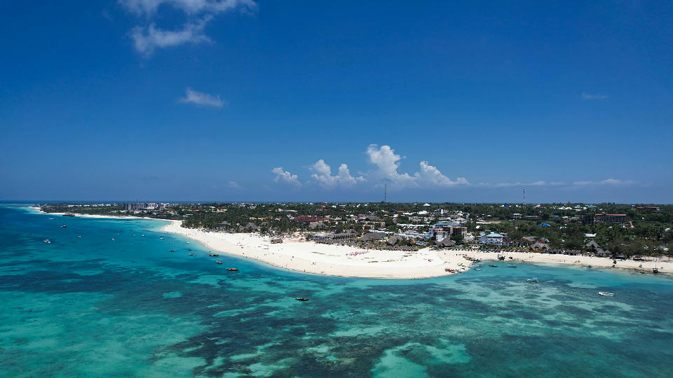 Drone view of Kendwa Beach with white sand, turquoise Indian Ocean, coral reef flats and the north-west coast of Zanzibar, Tanzania.