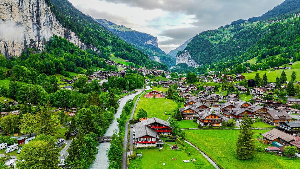 Aerial view of Lauterbrunnen village with wooden chalets along the valley floor and river in the Bernese Oberland, Switzerland.