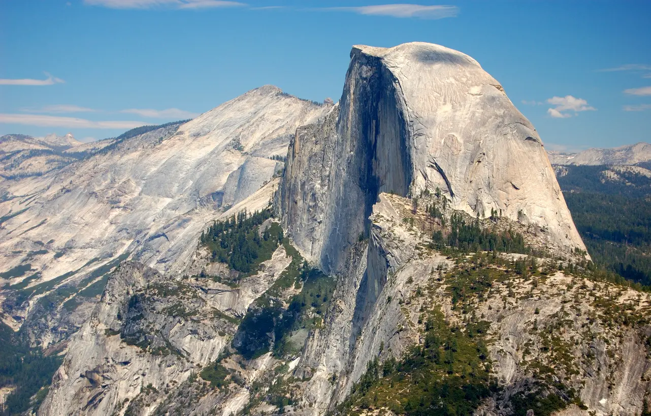 Half Dome Yosemite National Park with steep granite dome and surrounding mountain landscape under clear sky.