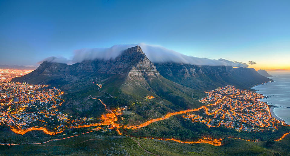 Table Mountain with tablecloth cloud above Cape Town and Camps Bay at sunset, South Africa.