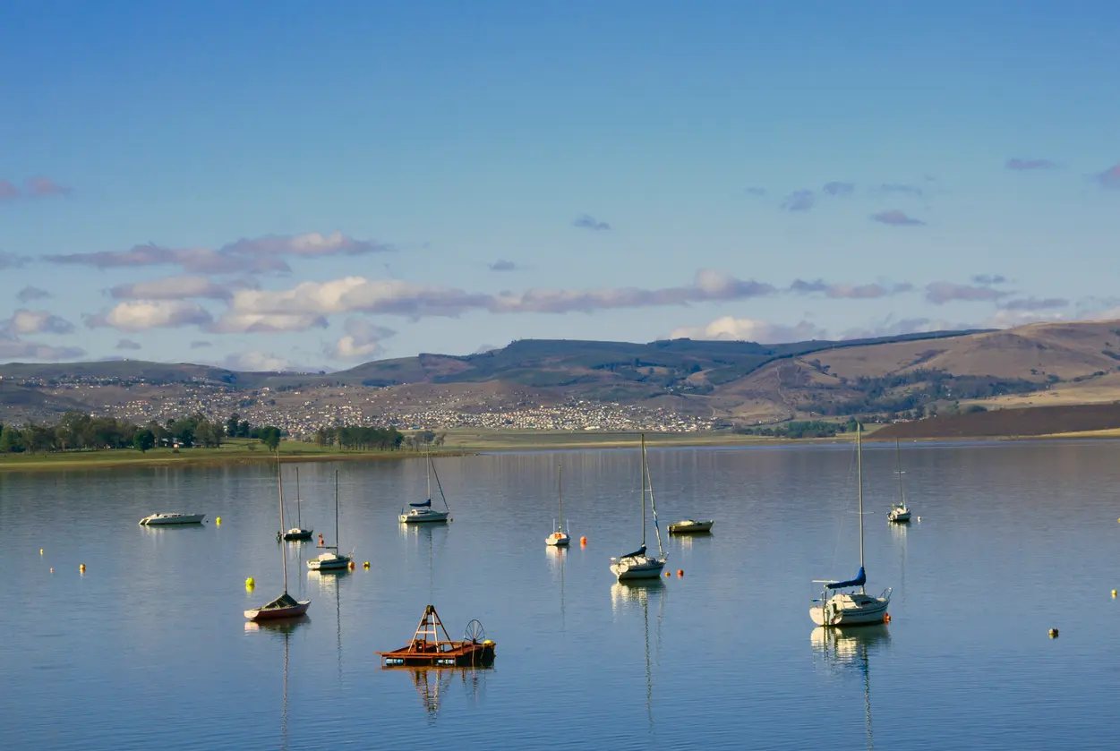 Sailing yachts moored on the still waters of Midmar Dam, with rolling hills and Midlands countryside in the background.