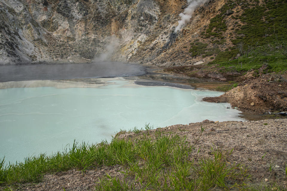 Milky turquoise water and steaming geothermal edge at Oyunuma Pond in Noboribetsu, Hokkaido, Japan.