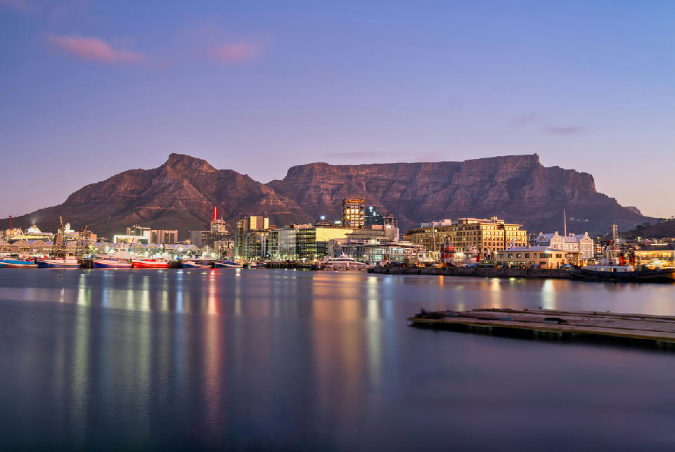 V&A Waterfront harbour with Table Mountain at sunset in Cape Town, South Africa.