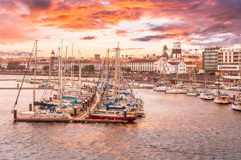 Yachts moored in Ponta Delgada Marina with the historic waterfront and church tower in the background on São Miguel Island, Azores.
