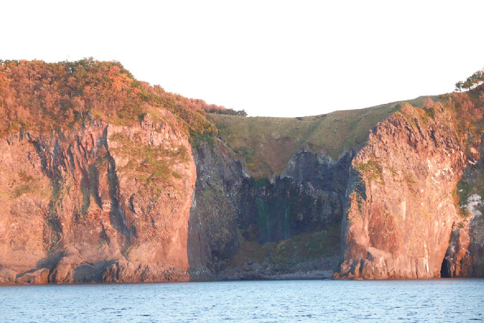 Furepe Waterfall flowing down a concave cliff at sunset in Shiretoko, Hokkaido