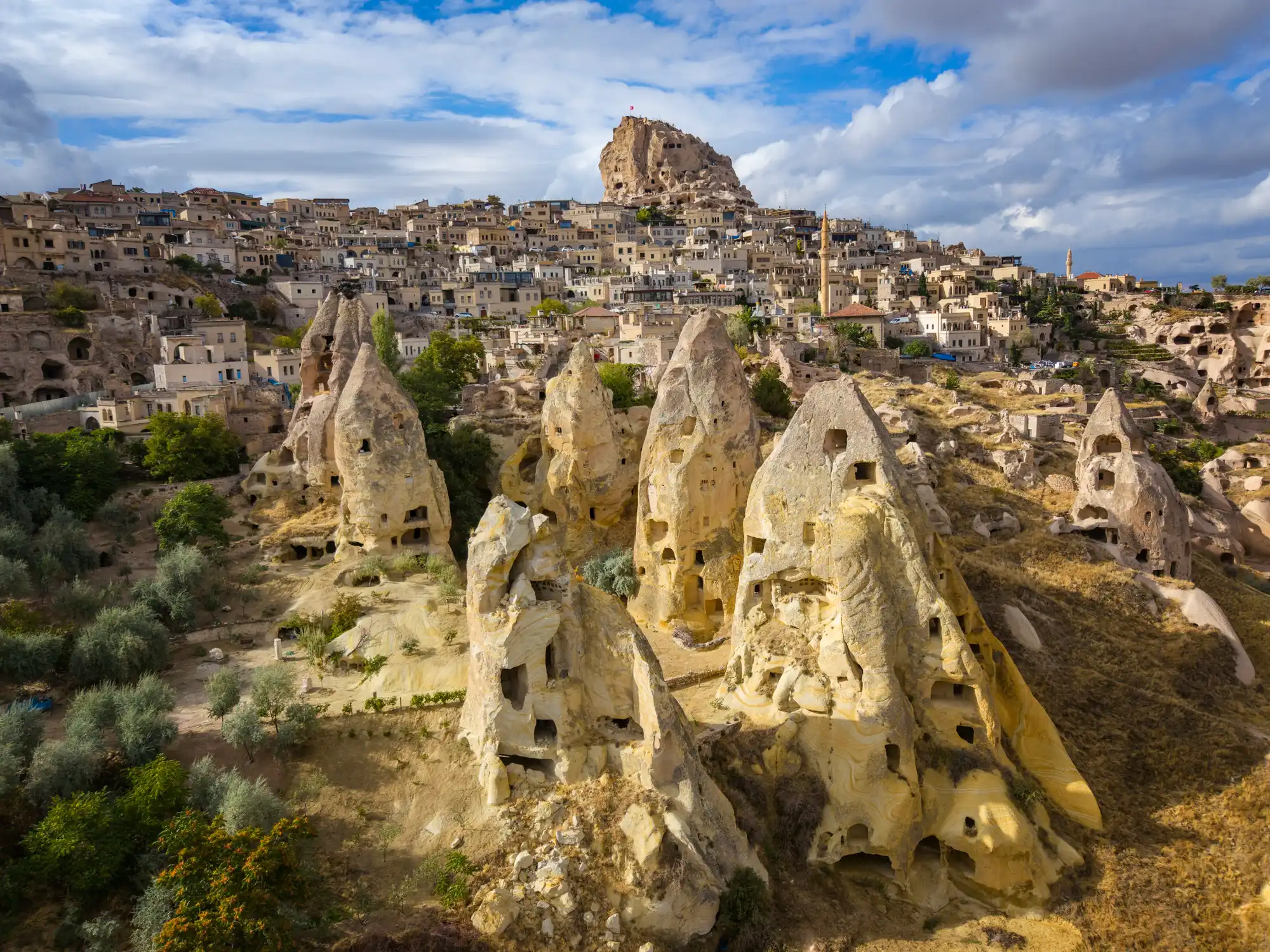 Uçhisar Castle overlooking rock-cut fairy chimneys and Uçhisar village in Cappadocia, Turkey.