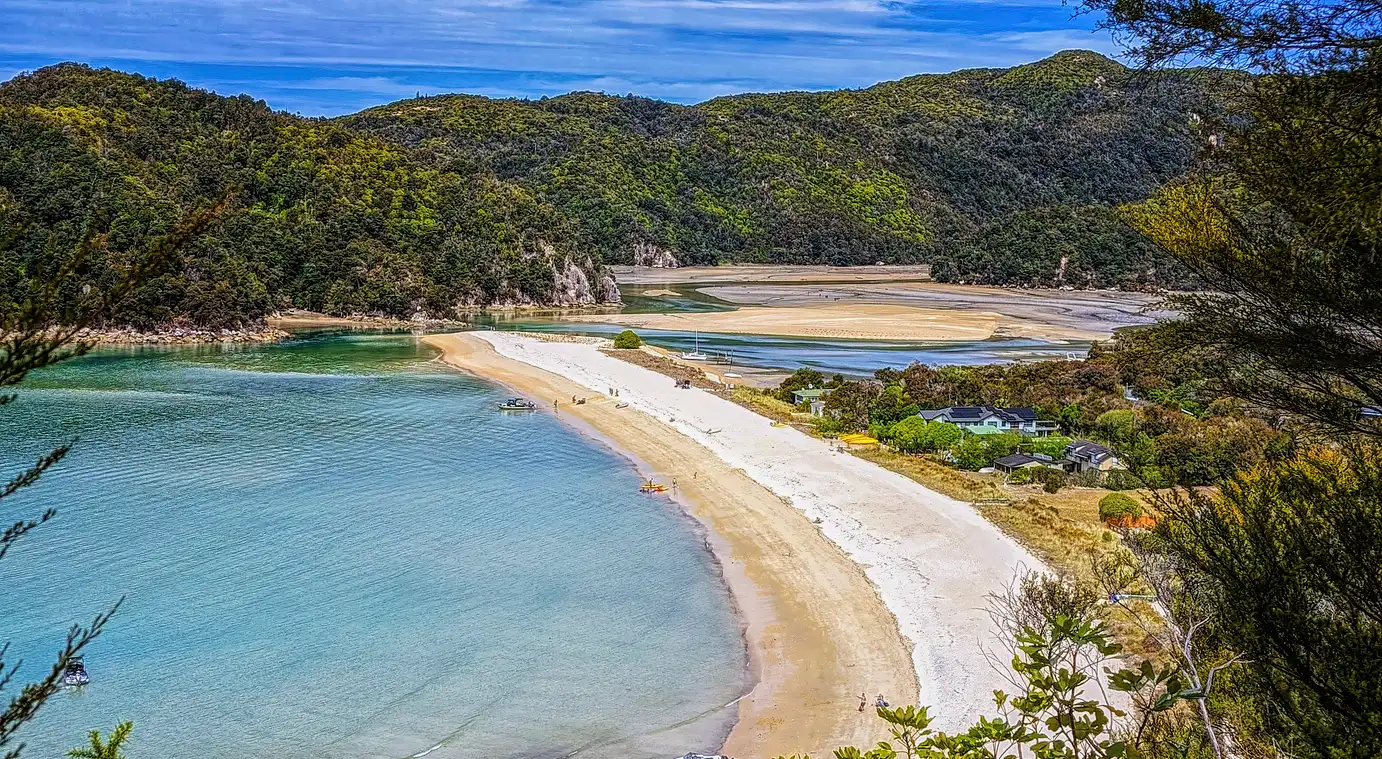 Low-tide sand flats and curving beach at Torrent Bay in Abel Tasman National Park, New Zealand.
