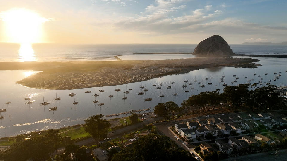 Morro Bay harbor with boats and Morro Rock at sunset California