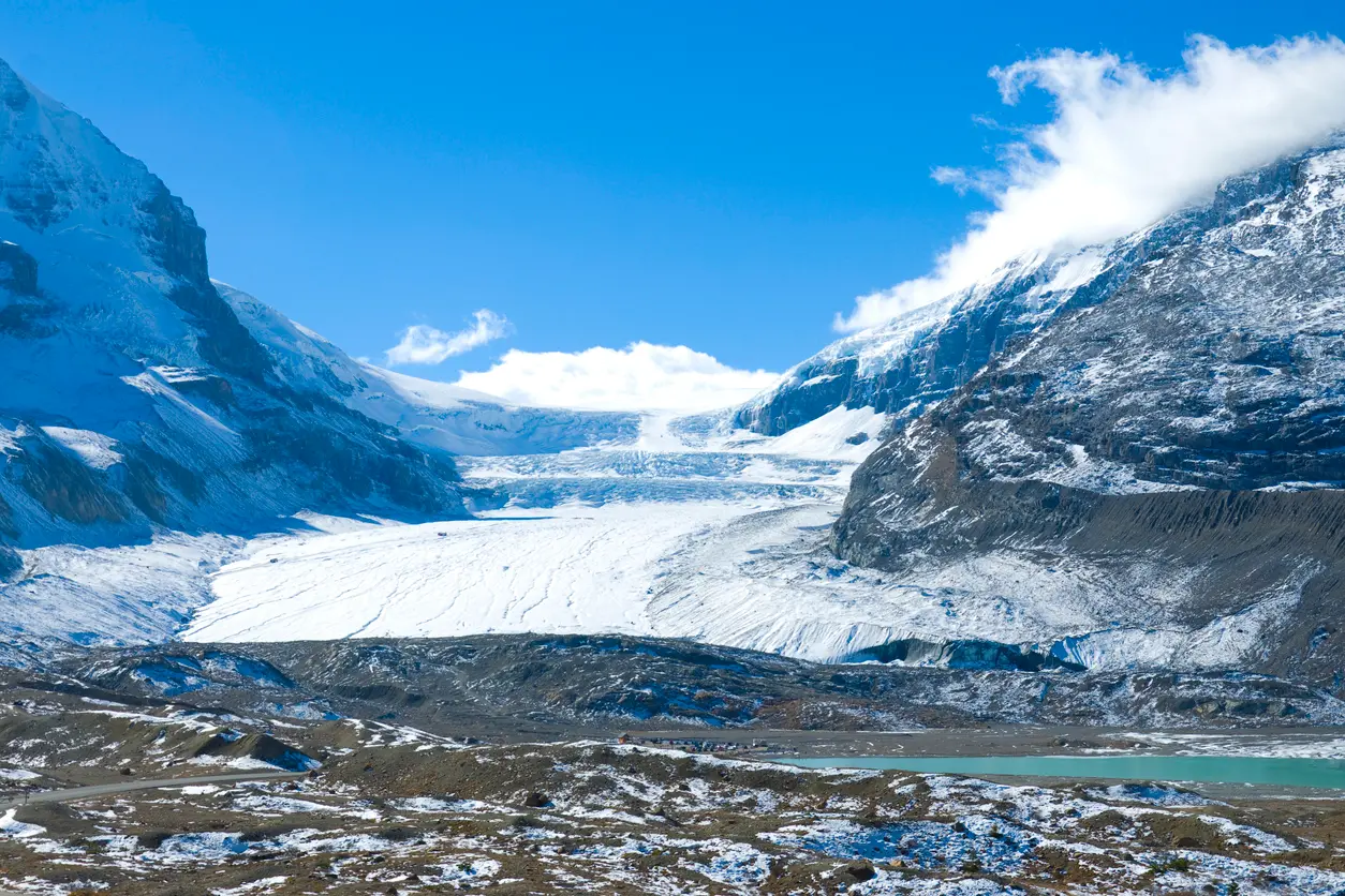 Athabasca Glacier flowing from the Columbia Icefield in Jasper National Park, surrounded by snow-covered mountains and rocky foreground terrain