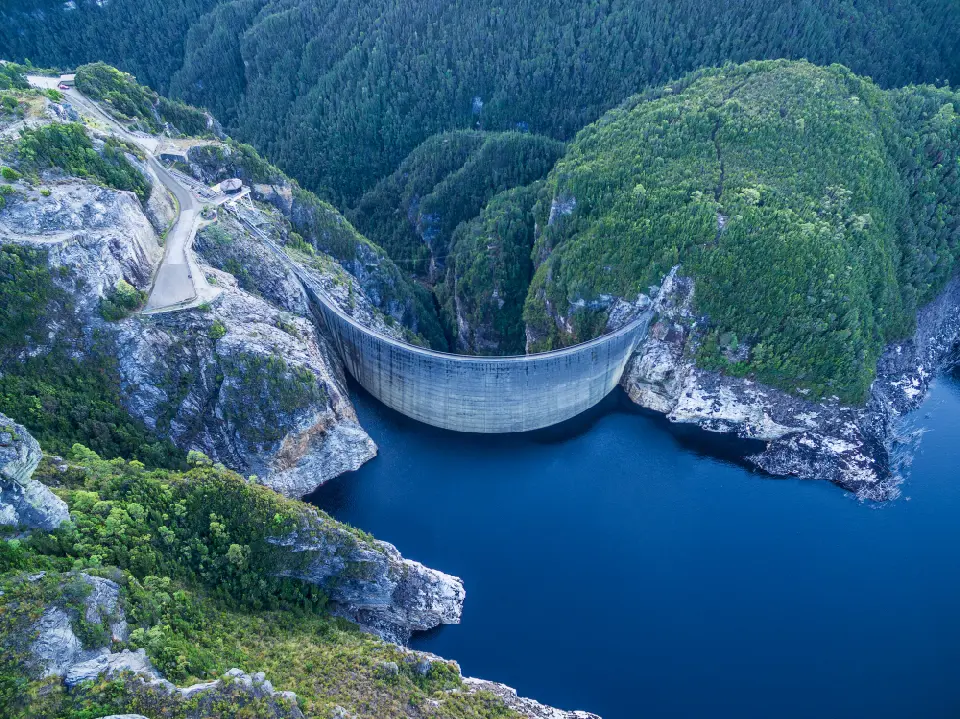 Aerial view of Gordon Dam and Lake Gordon surrounded by forested mountains in southwest Tasmania, Australia.