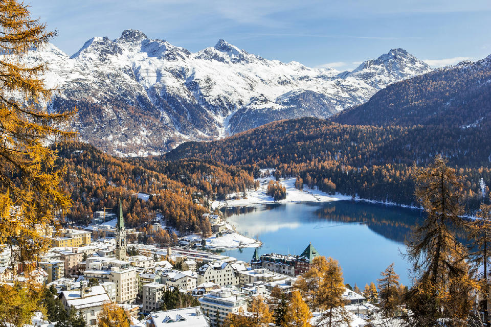 View over St. Moritz and its alpine lake with snow-dusted buildings and autumn forest in Engadin, Switzerland.