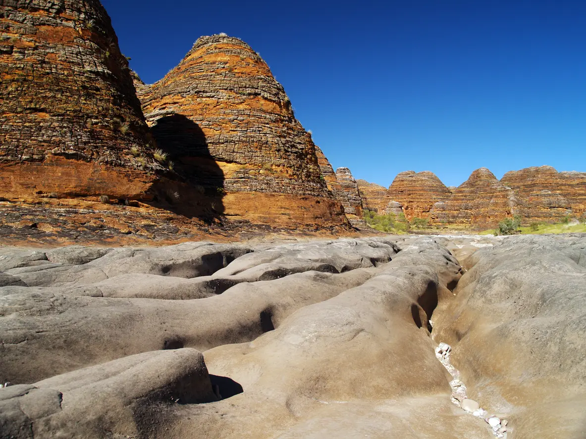 Eroded channels in the dry bed of Piccaninny Creek lead between the striped sandstone domes of the Bungle Bungle Range.