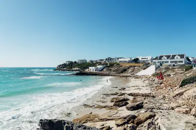 Seaside houses above a rocky beach and turquoise ocean in Arniston on the Western Cape coast of South Africa.