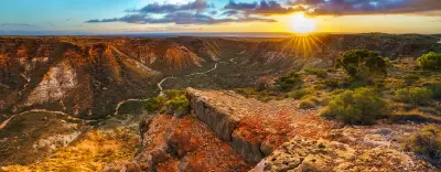 Sunrise illuminates the rugged cliffs and winding valley of Charles Knife Canyon.
