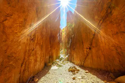 Midday sunlight streams between the towering orange rock walls of Standley Chasm.