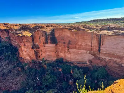 Layered red sandstone cliffs and vegetation inside Kings Canyon in Watarrka National Park, Northern Territory, Australia.
