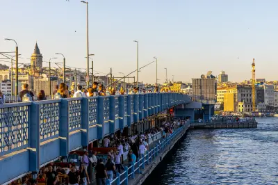People fishing from Galata Bridge in Istanbul with waterfront restaurants below and Galata Tower in the background.