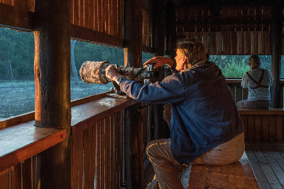 Photographers using long telephoto lenses inside the Lake Panic Hide overlooking the water in Kruger National Park.