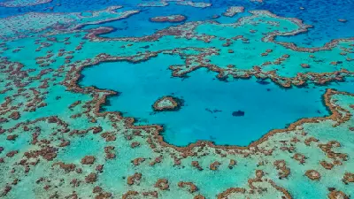 Wide aerial view of Heart Reef surrounded by extensive coral formations and turquoise lagoons in the Great Barrier Reef, Australia.