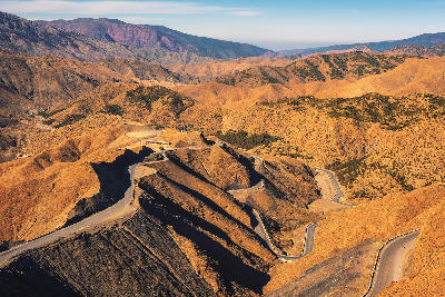 Winding mountain road crossing Tizi n’Tichka Pass in Morocco’s Atlas Mountains with layered canyon terrain and arid ridgelines