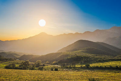 Golden evening light over farmland and rolling hills beneath the Swartberg Mountains near Oudtshoorn in the Little Karoo, Western Cape, South Africa