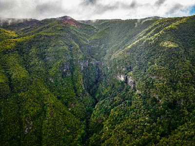 Aerial view of Risco Waterfall cascading into a deep, forested ravine in the Rabaçal valley, Madeira.