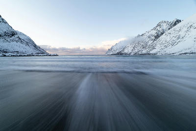 Long-exposure shoreline at Ersfjord showing blurred water and snow-covered mountains on Senja