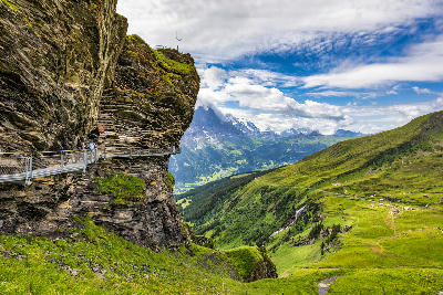 Cliff walkway carved into rock face above Grindelwald valley with views of the Bernese Alps, Switzerland.