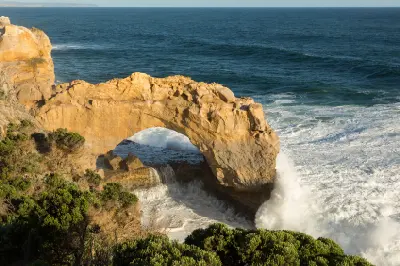 Large wave crashing beneath the limestone formation of The Arch on Victoria’s Great Ocean Road.