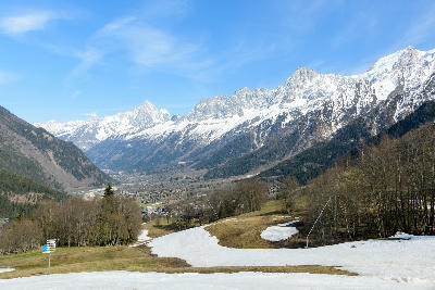 Wide view of Chamonix Valley with town on the valley floor and snow-covered Mont Blanc massif in the French Alps.