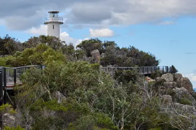 Cape Tourville Lighthouse and elevated circuit boardwalk surrounded by coastal vegetation in Freycinet National Park, Tasmania.