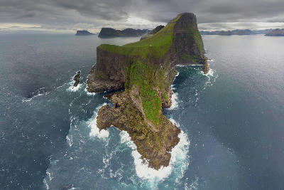 Aerial view of steep green cliffs and narrow ridge on Kalsoy Island surrounded by the North Atlantic in the Northern Islands of the Faroe Islands.