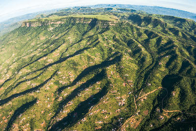 Aerial panorama of the Valley of a Thousand Hills showing green ridges, winding valleys, rural homesteads and layered escarpments stretching across KwaZulu-Natal, South Africa.