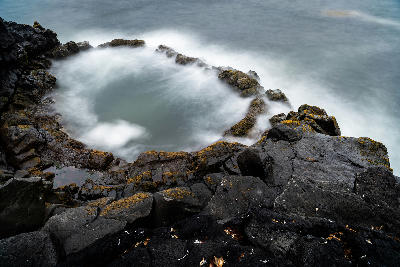 Circular lava pool at Brimketill on the Reykjanes Peninsula, Iceland, with waves surging into the basin.