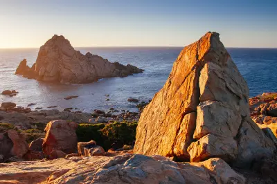 Sugarloaf Rock and large granite formations glowing in golden sunset light at Cape Naturaliste, Western Australia.