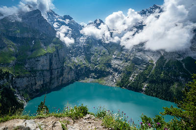 Elevated view of Oeschinen Lake surrounded by steep cliffs and alpine peaks above Kandersteg in the Bernese Oberland, Switzerland.