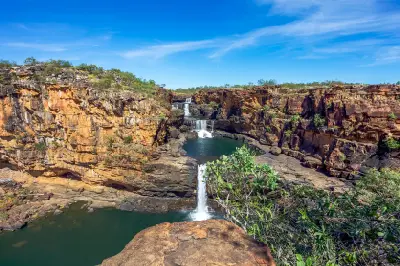 Multi-tiered Mitchell Falls cascade between rugged sandstone cliffs into deep pools on the remote Mitchell Plateau.