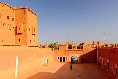 Adobe courtyard and fortified walls inside Kasbah Taourirt in Ouarzazate, Morocco, under clear desert light.