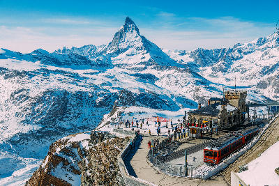 Gornergrat summit station with visitors and cogwheel train overlooking the Matterhorn and surrounding alpine glaciers above Zermatt