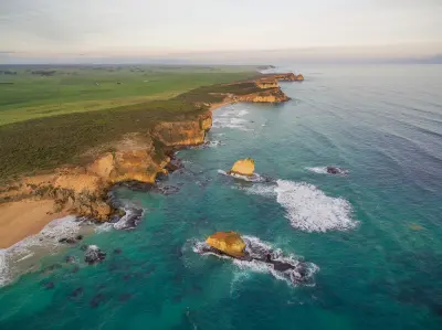 Aerial view of Childers Cove with sandy beach, offshore rock stacks, limestone headlands and farmland in Victoria.