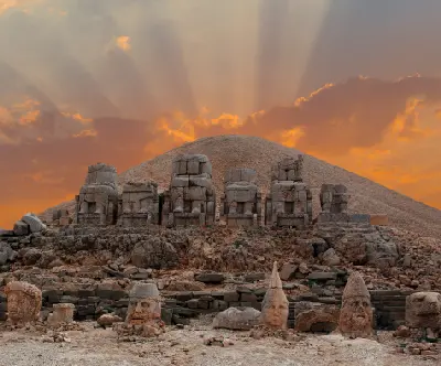 Colossal stone heads and statues beneath the burial mound on Mount Nemrut at sunrise.