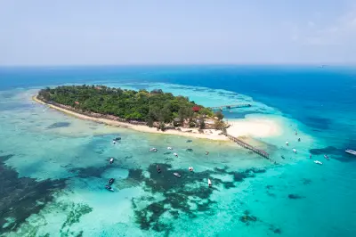 Drone view of Prison Island with tropical forest, white sand beaches, wooden jetties, and turquoise Indian Ocean, Zanzibar, Tanzania.