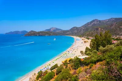 Panoramic view of Ölüdeniz Beach, turquoise sea and forested mountains near Fethiye, Türkiye.