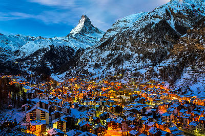 Zermatt village at dusk with illuminated chalets beneath the Matterhorn, Switzerland.