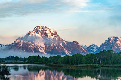 Mount Moran reflected in the Snake River at Oxbow Bend with soft sunrise light and low mist, Grand Teton National Park, Wyoming.