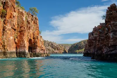 Powerful turquoise tidal water surges sideways through a narrow gap between rugged red cliffs at Horizontal Falls in Talbot Bay