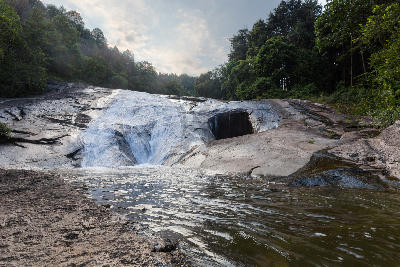 Water flowing over smooth granite rock terraces at Debengeni Falls in Magoebaskloof, Limpopo, South Africa.