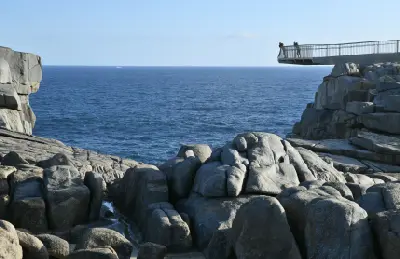 Visitors standing on the cantilevered viewing platform above the granite cliffs at The Gap near Albany, Western Australia.